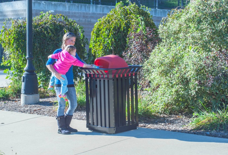 women with a child throwing trash into a receptacle