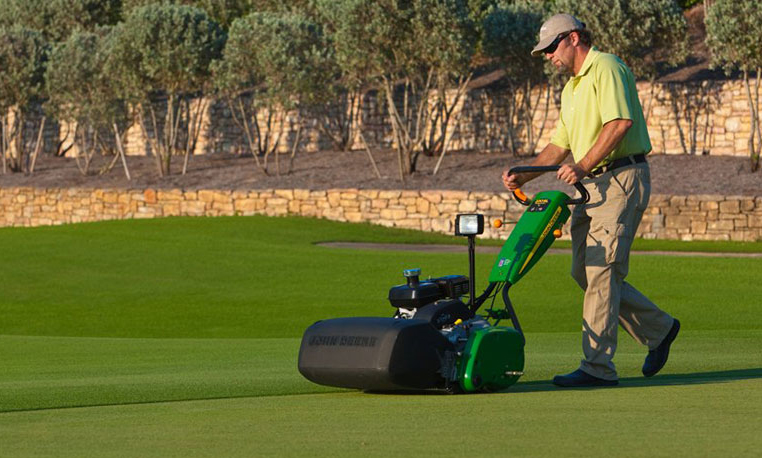 greens keeper mowing a green